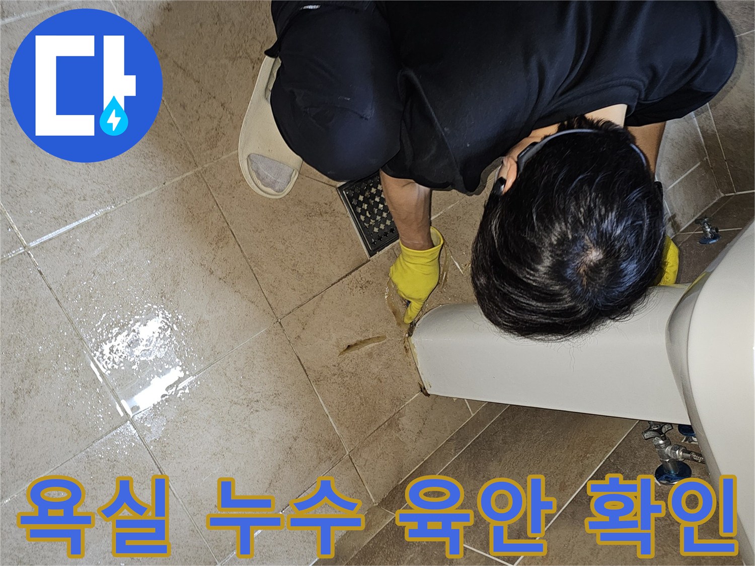 누수 엔지니어가-노란색 장갑을 끼고-욕실 바닥의 젖은 타일과-세면대 주변을-세심하게 관찰하며-누수 지점을 탐색합니다