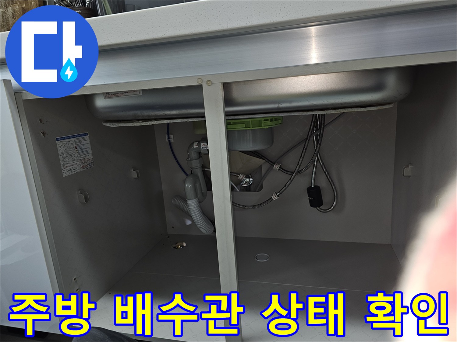 주방 싱크대 아래 배수관과 수도 연결부를 점검하는 모습으로-누수 여부를 확인하기 위한 상세한 검사 과정입니다.