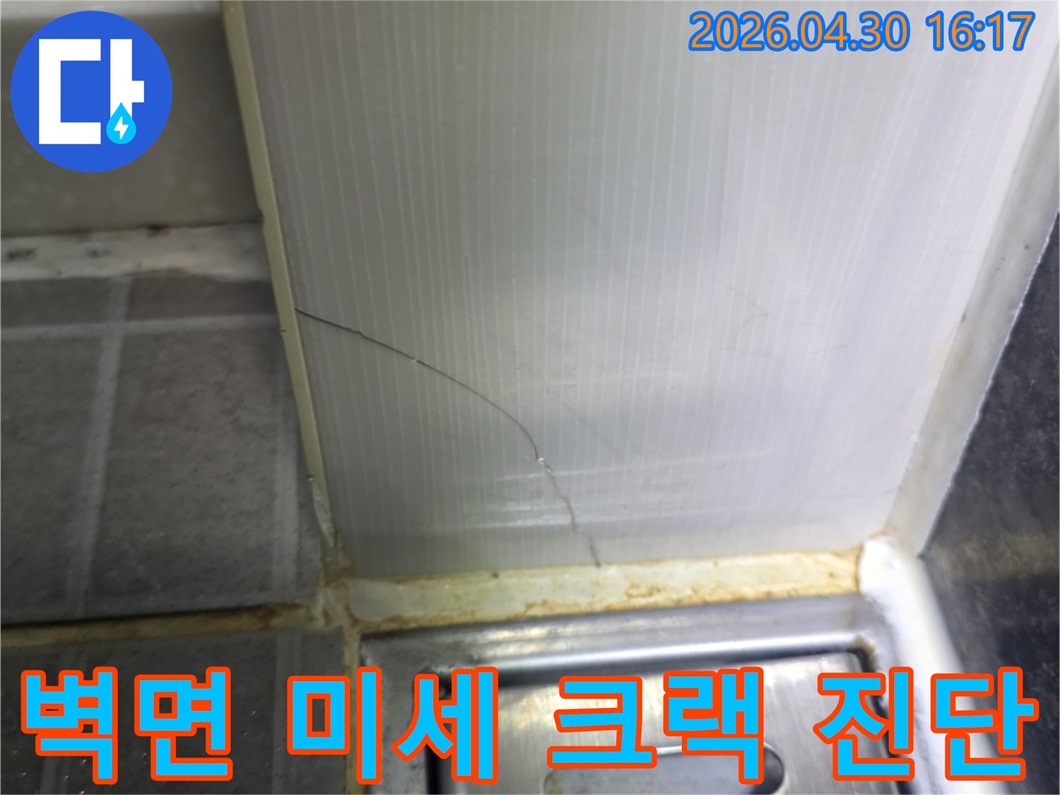 욕실 벽면 패널과-타일 사이의-실리콘에 발생한-아주 미세한 균열을-확대한 모습으로-정밀 진단이 필요한 상태를 보여줍니다.