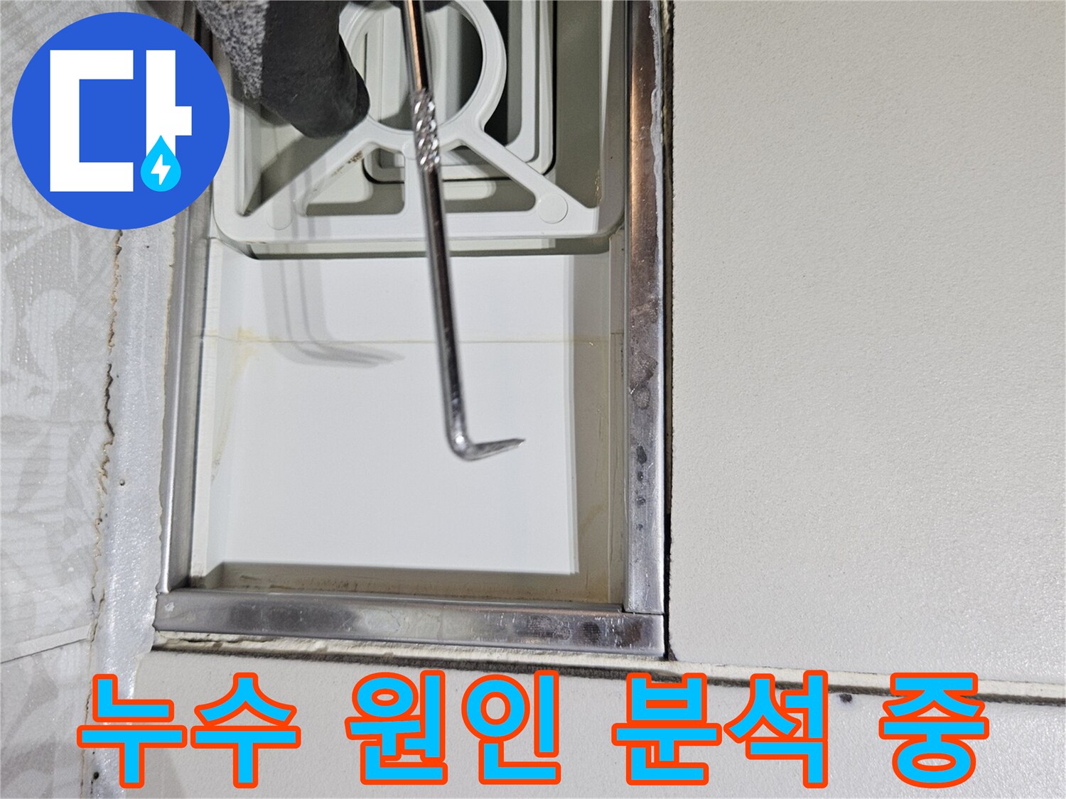 누수 전문 기술자가-특수 도구로-벽면 틈새를-정밀하게-조사하며-누수 원인을-분석하는 장면입니다