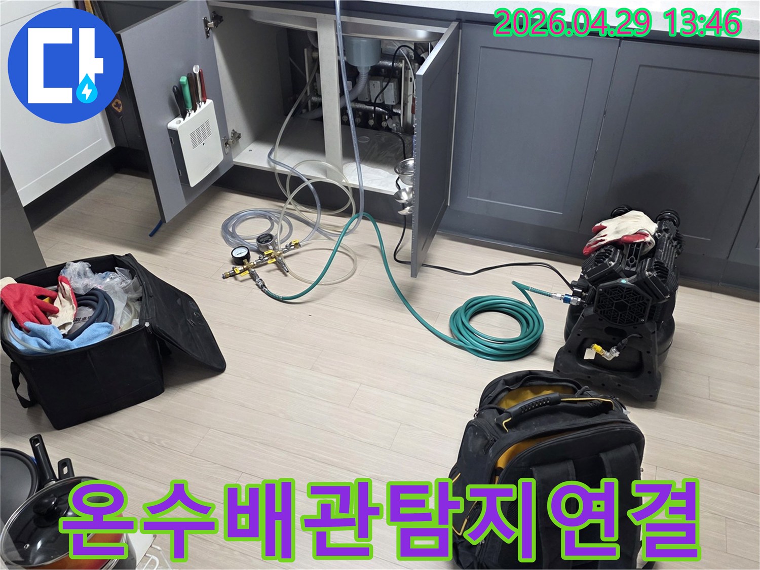 안양 비산 삼성 래미안 아파트의 주방에서-온수 배관의 누수를 확인하기 위해-압력 게이지와 호스-그리고 공기 압축 장비를-연결하는 작업이 진행 중입니다