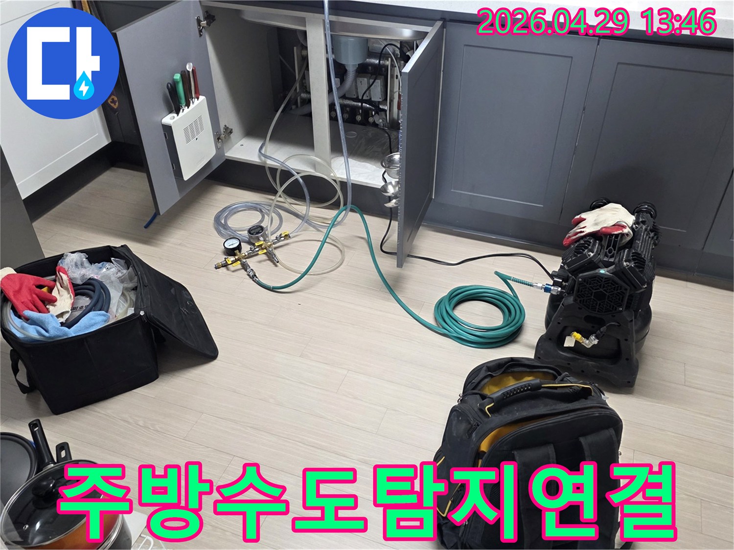 안양 삼성 래미안 아파트의 주방에서-수도 배관의 누수를 확인하기 위해-압력 게이지와 호스-그리고 공기 압축 장비를-연결하는 작업이 진행 중입니다