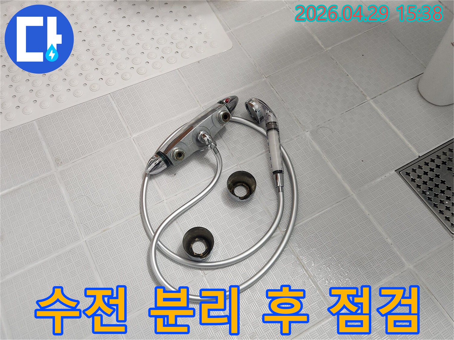 욕실 바닥에-해체된-오래된-수전과-샤워기가-놓여있으며-누수 점검을-위해-분리된-모습입니다