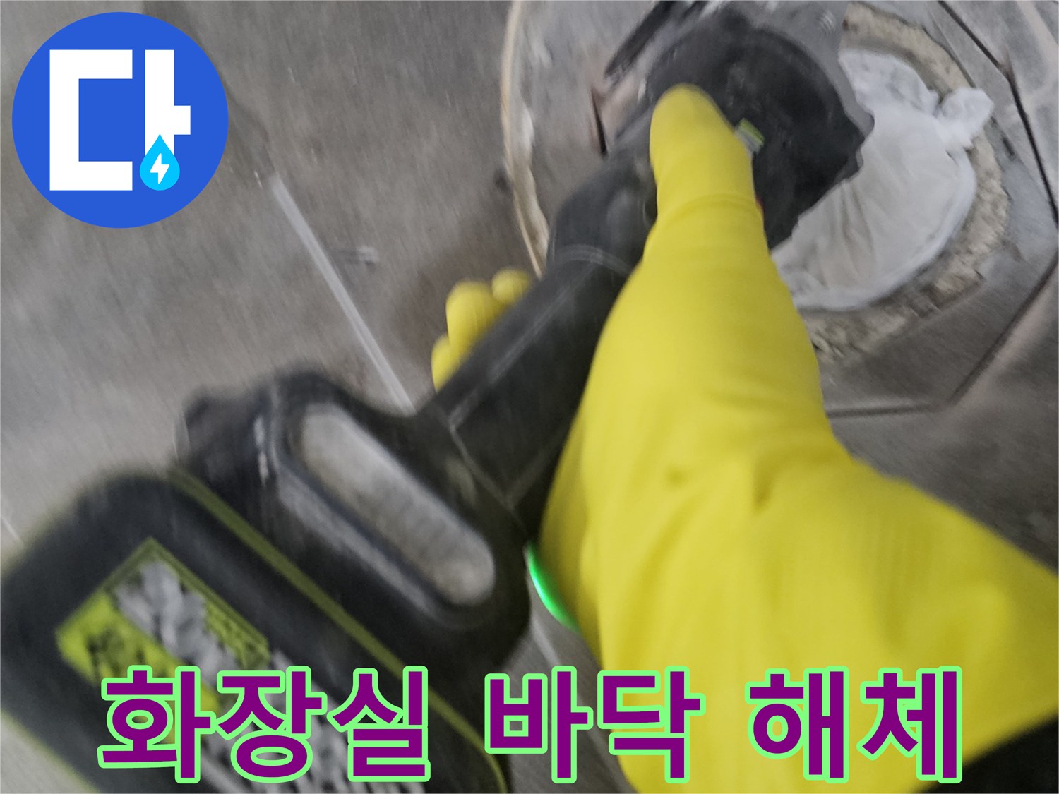 노란 장갑을 낀 작업자가-전동 커터로-오수 배관 주변의 바닥 타일을-정확하게 잘라내어-해체하는 모습입니다.