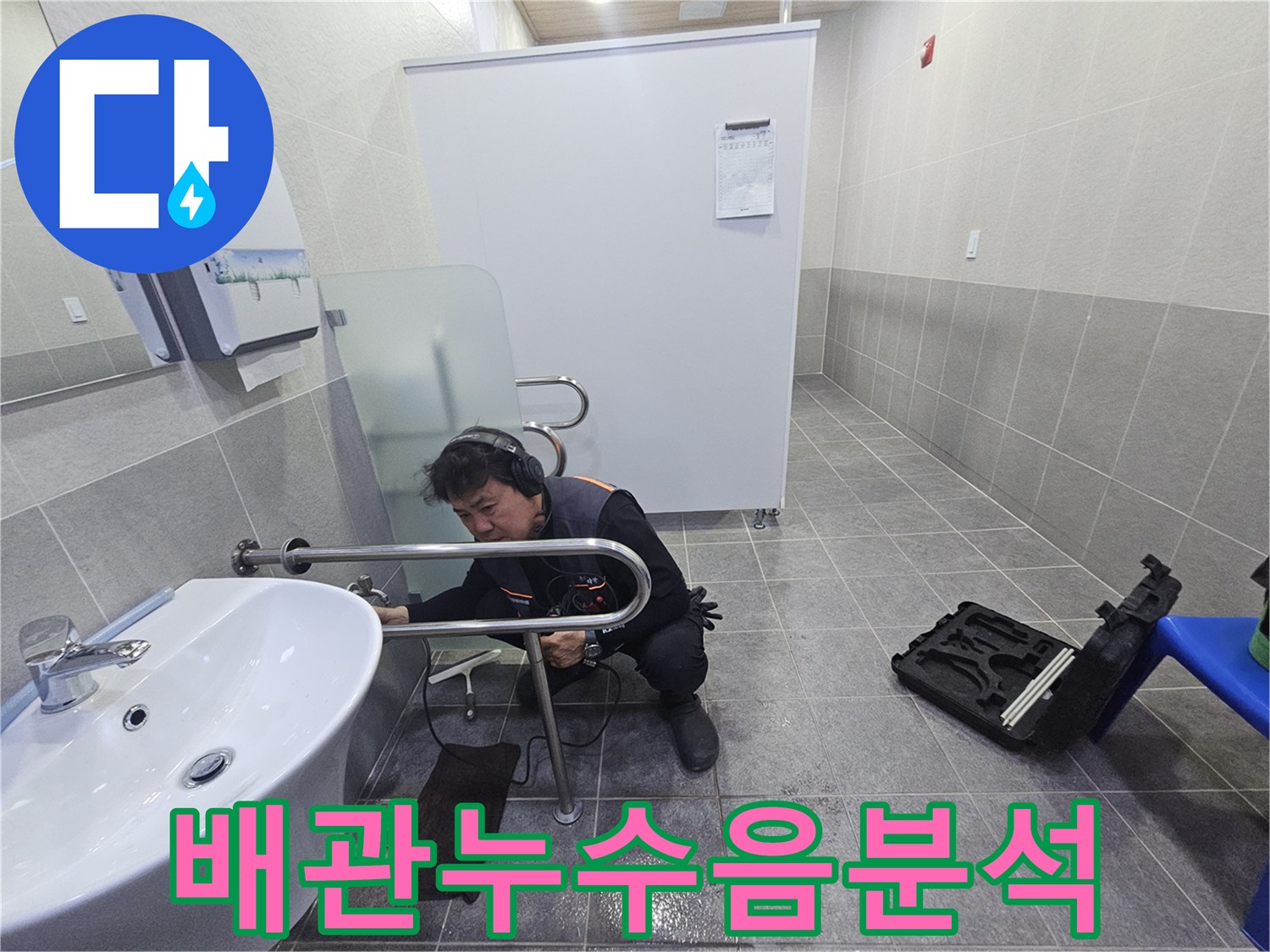 누수 전문 엔지니어가-청음식 탐지기로-욕실 배관의 누수음을 분석하고 있습니다.