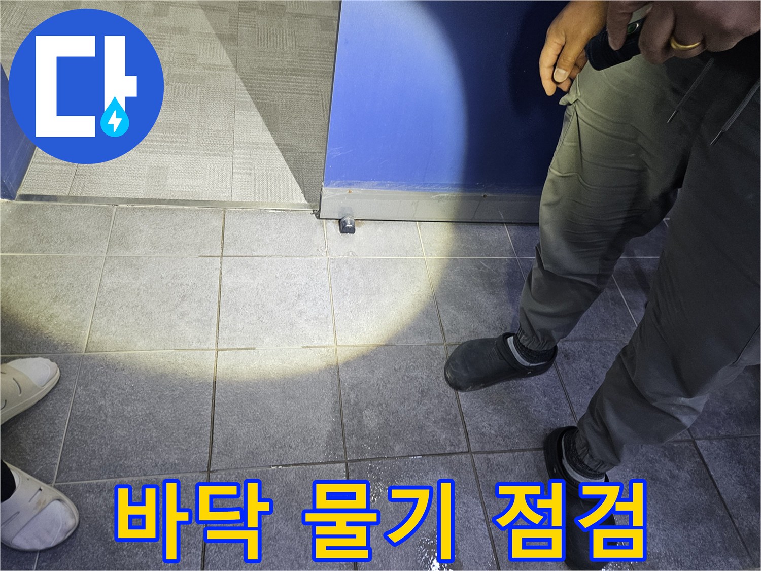 누수 탐지 전문가가 바닥에 고인 물기를 보고-누수 발생 여부와 대략적인 위치를 파악하고 있습니다.