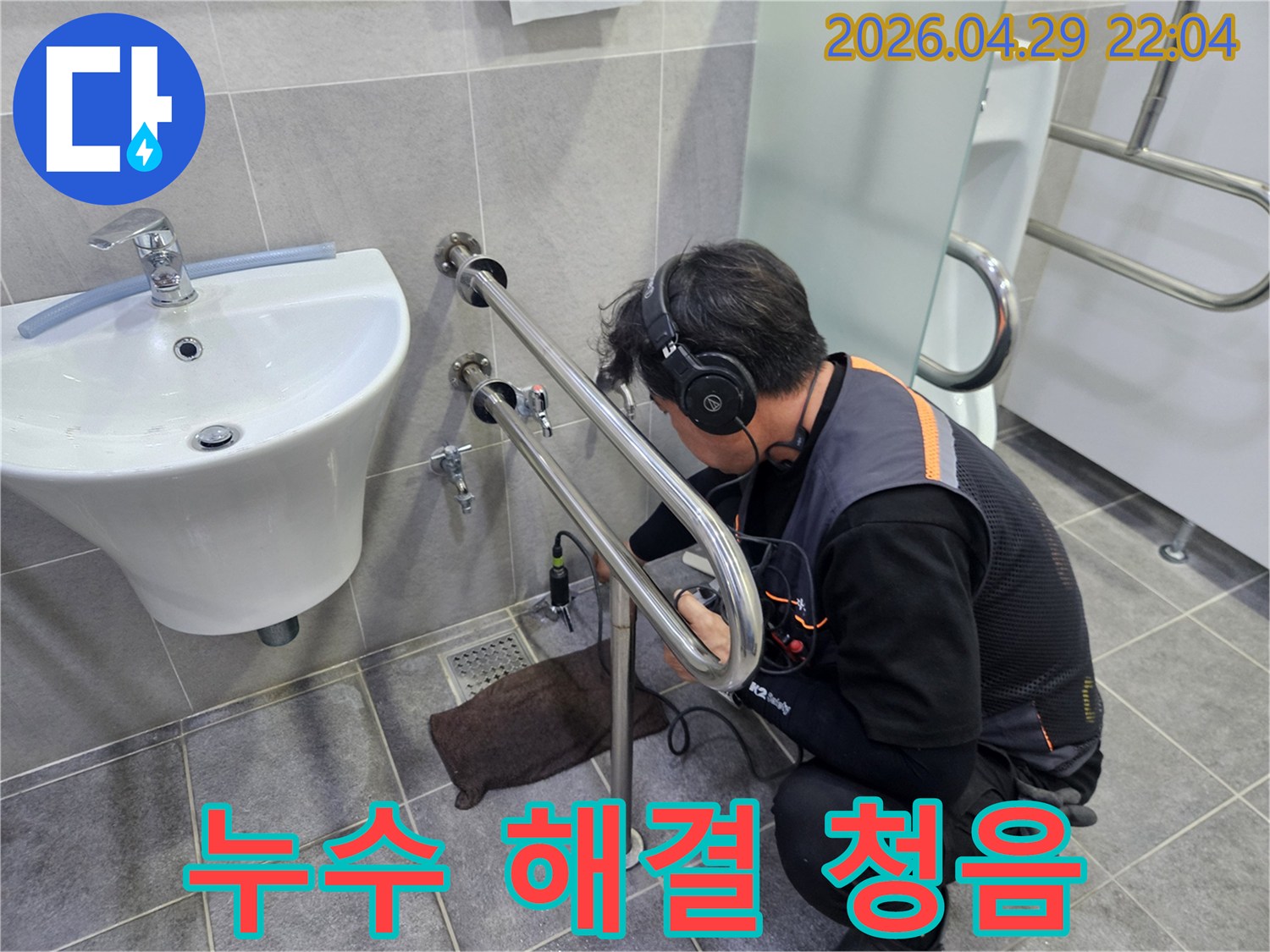 전문가가-누수탐지 장비를 이용해-화장실 배관에서 발생하는-미세한 소리를-집중적으로 듣는 모습