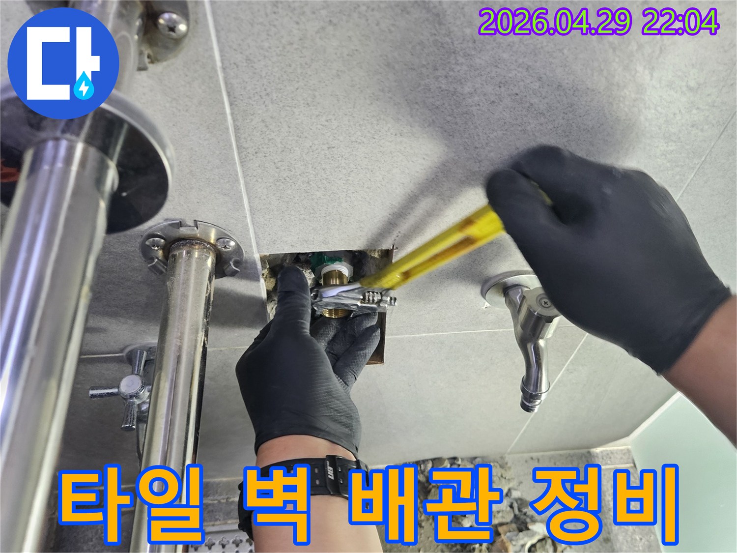 타일 벽 속에 숨겨진 배관에서 발생한-누수를 정비하는 전문 작업 현장입니다