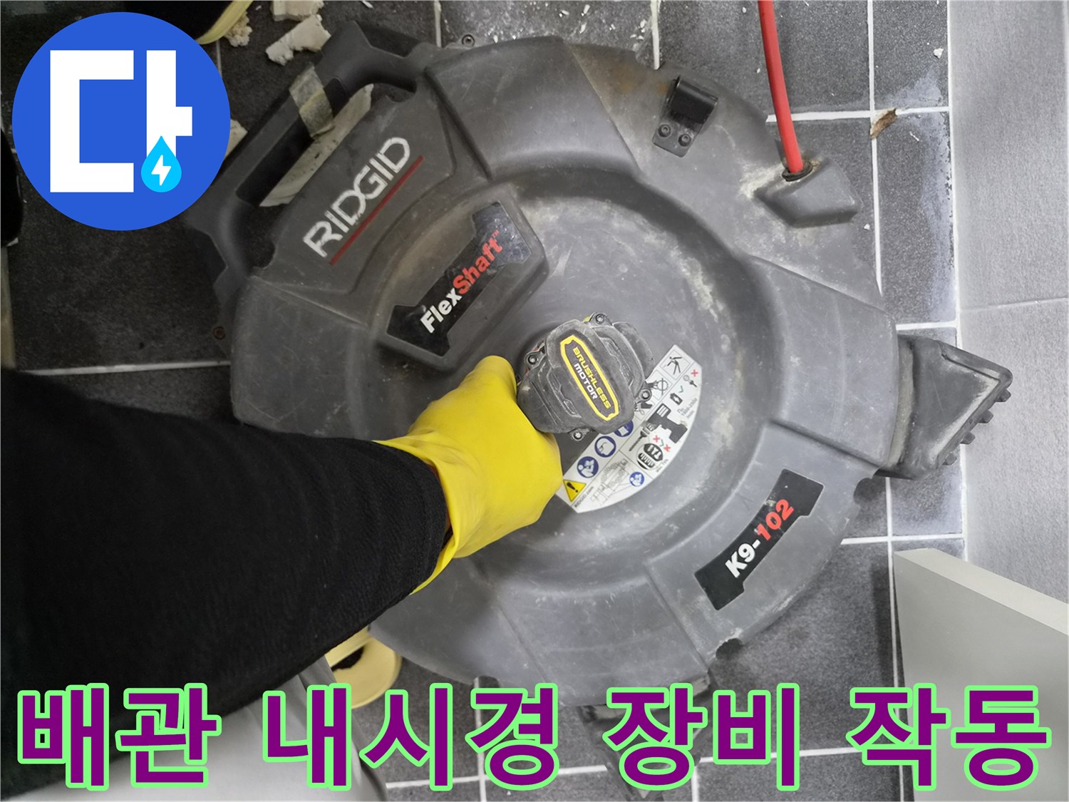 노란색 장갑을 낀 작업자가-배관 내부를 확인하기 위해-리지드 플렉스샤프트 K9-102 장비를 조작하는 모습입니다.