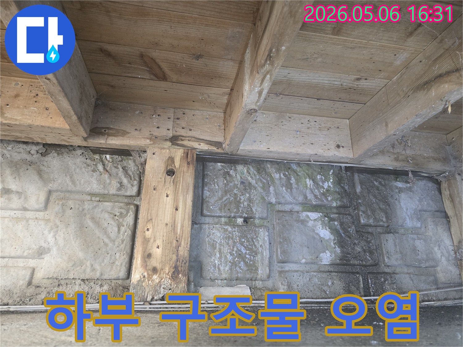 건물 하부의-목재 구조물과 벽면에-물기로 인한-오염과 변색이-뚜렷하게 나타난-누수 현장