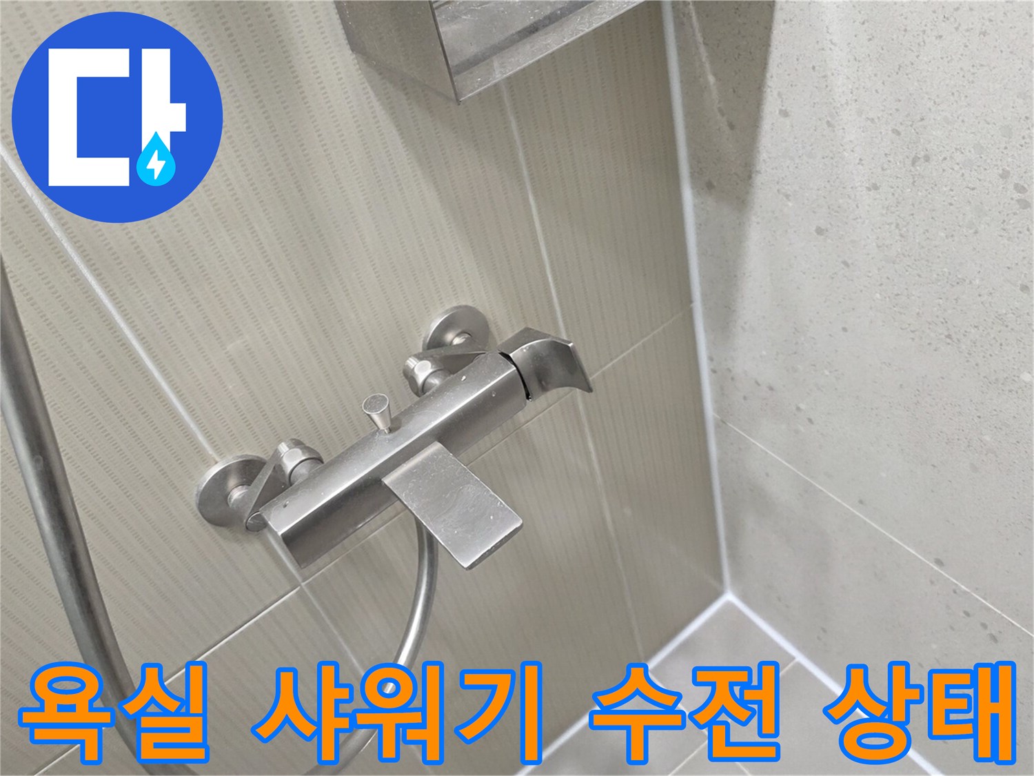 밝은 베이지색 타일 벽면에 설치된 스테인리스 소재의 샤워 수전과 샤워 호스 모습입니다.