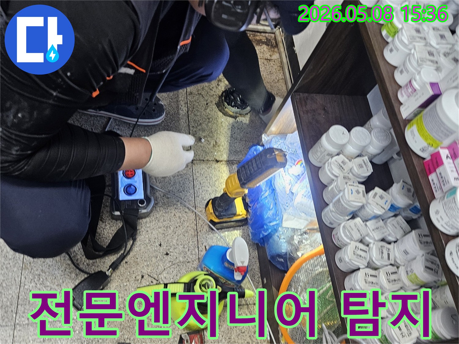숙련된 누수 엔지니어가-싱크대 아래에서-청음 탐지 장비로-배관 누수 지점을 확인하는 장면