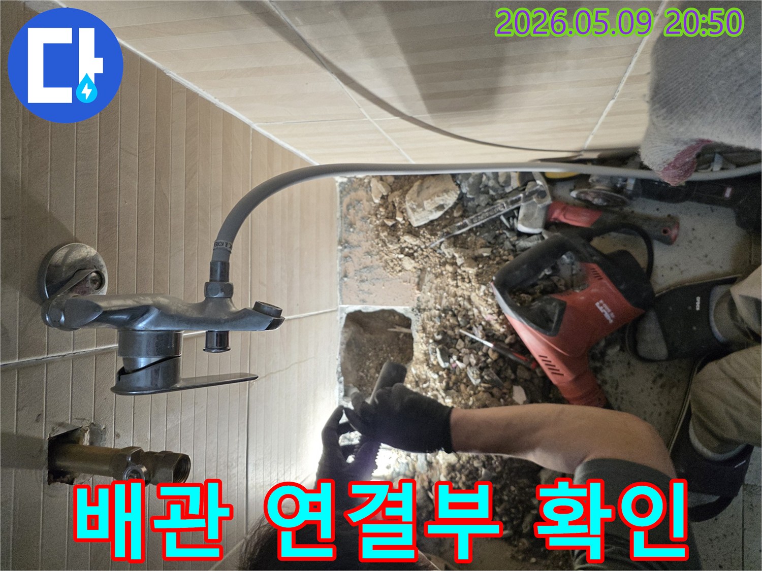 이 이미지는-성남 수정구의 한 빌라에서-누수 공사 중-새롭게 연결된 배관 부위를-전문가가 꼼꼼하게 확인하며-누수 가능성을 차단하는-작업 현장을 보여줍니다.