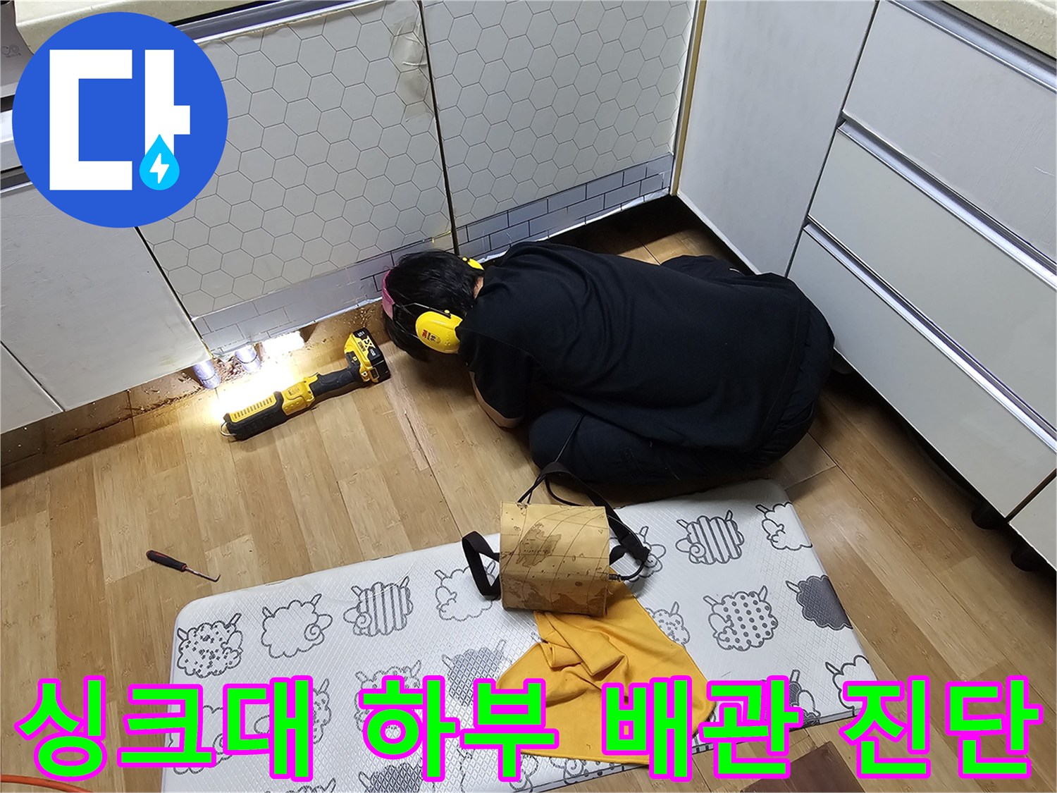 어두운 싱크대 밑 공간의 배관 누수 여부를 확인하는 작업 현장