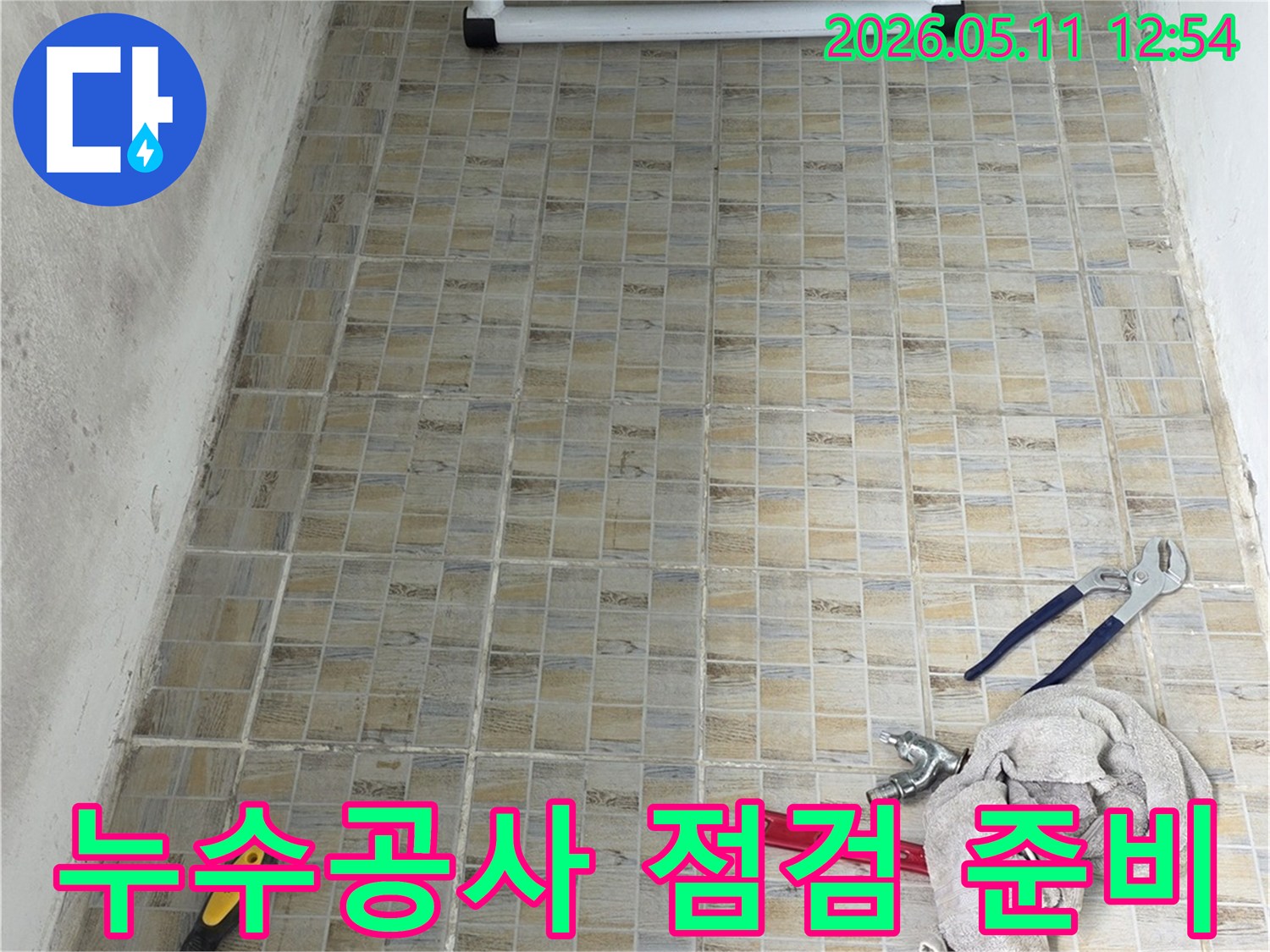누수 공사 현장에서-타일 벽면과-작업에 필요한 공구들이 놓여있는 모습