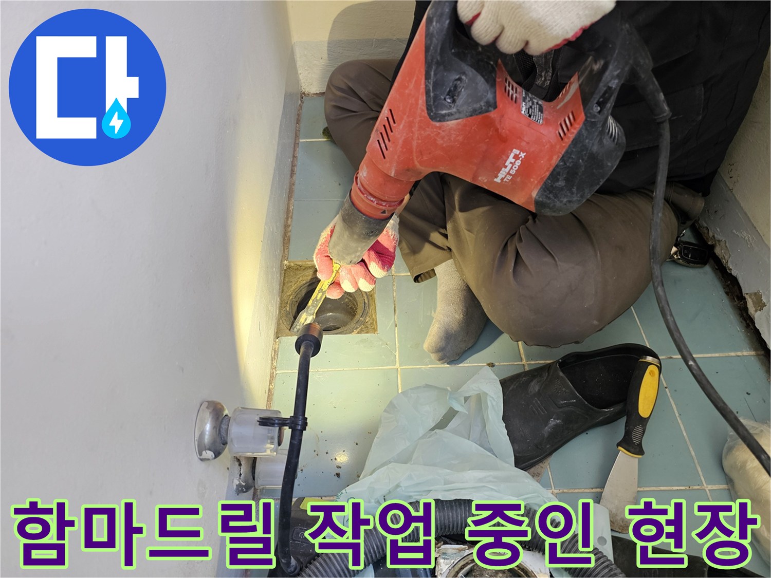 배수구 주변의-손상된 타일을 제거하기 위해 함마드릴을 사용하는 장면입니다.