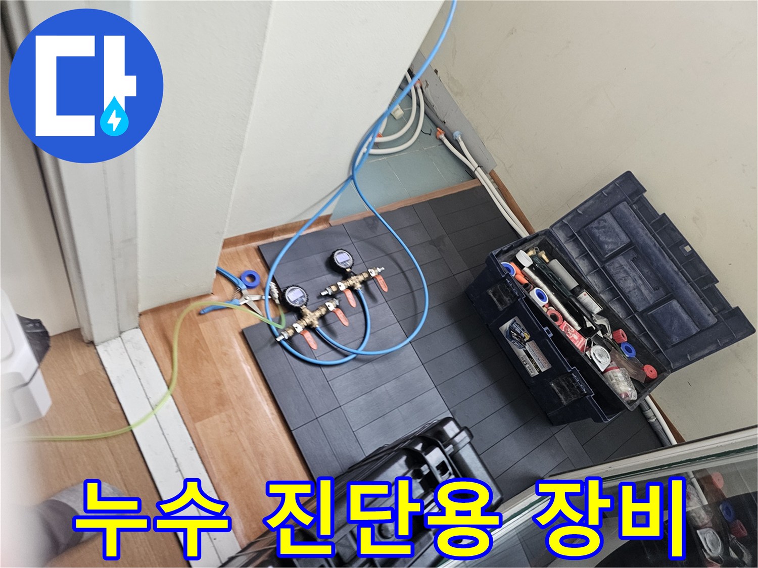 세탁실 바닥에 놓인 누수 탐지용 압력계와 공기 주입 호스 세트