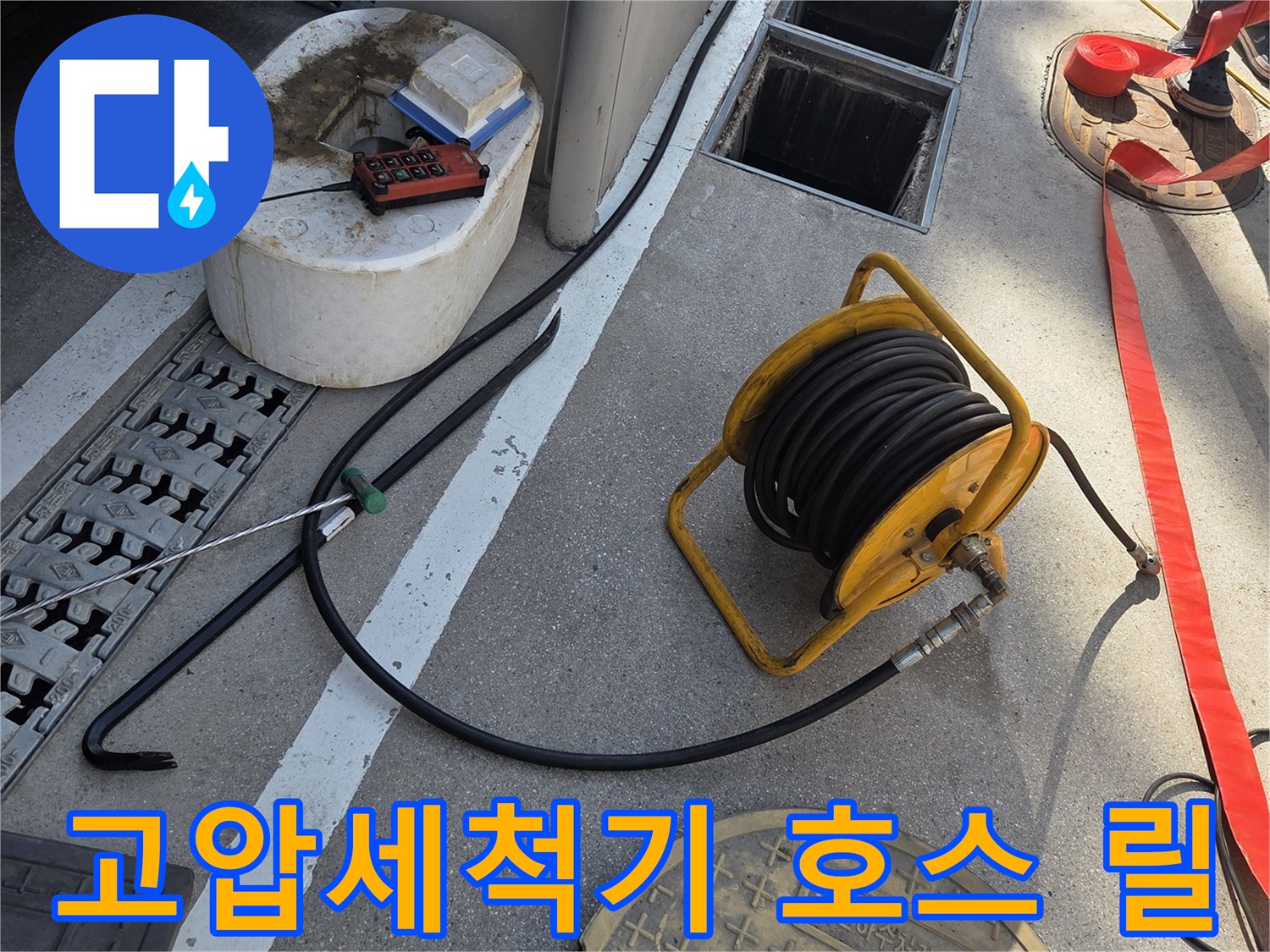 맨홀 근처에 배치된 노란색 고압 세척 호스 릴과 작업 장비