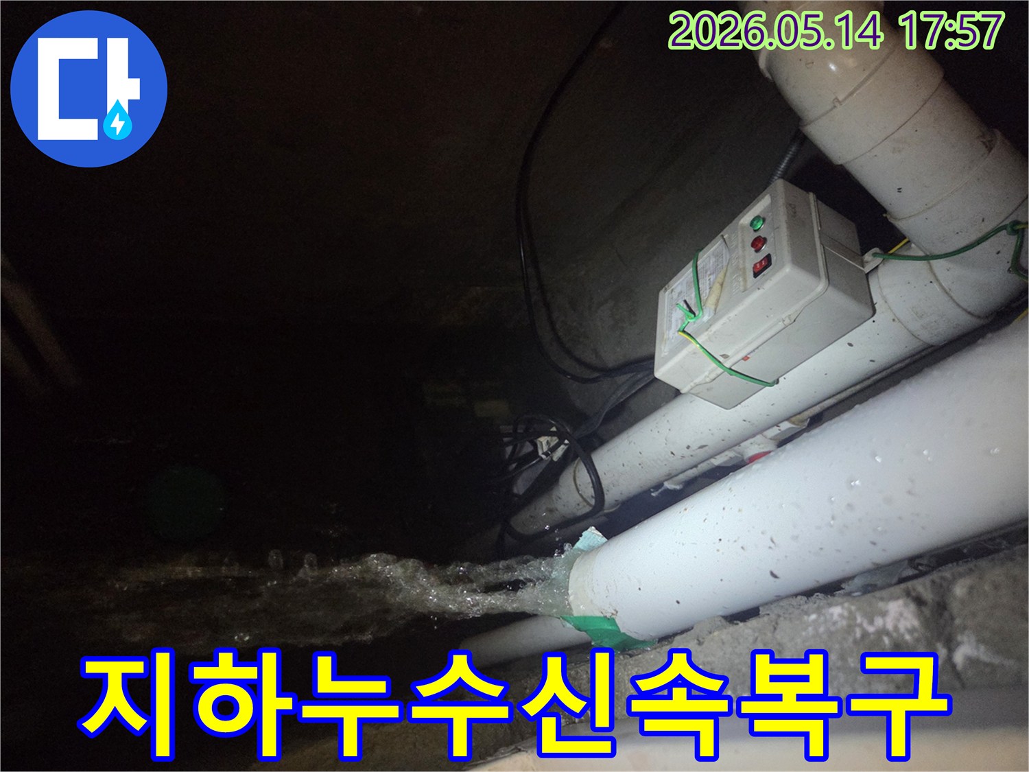 어두운 지하 공간에서-파이프에서 물이 강하게 뿜어져 나오는-누수 현장을 보여주는 사진입니다-전기 제어 박스와 배관들이 함께 보입니다.
