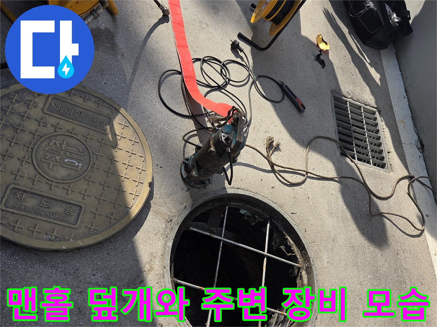 열려 있는 맨홀과 그 옆에 준비된 고압 세척 호스 사진입니다.