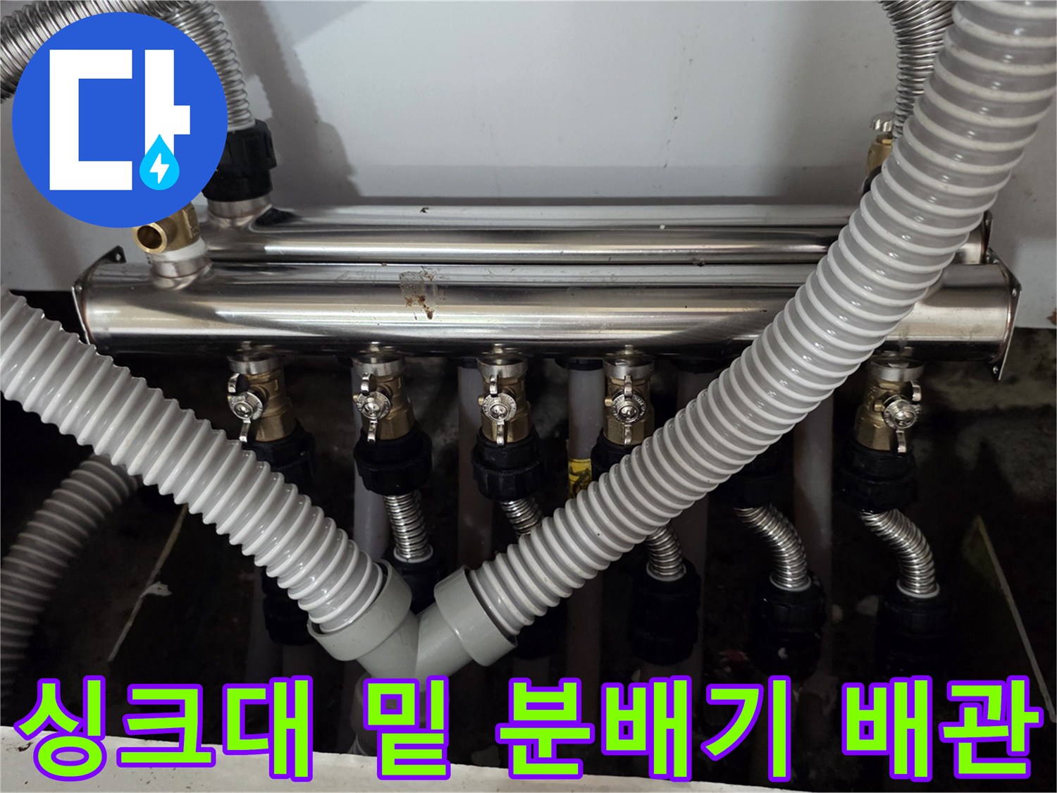 싱크대 하단 공간에 배치된 금속제 분배기와 연결된 주름 배관들