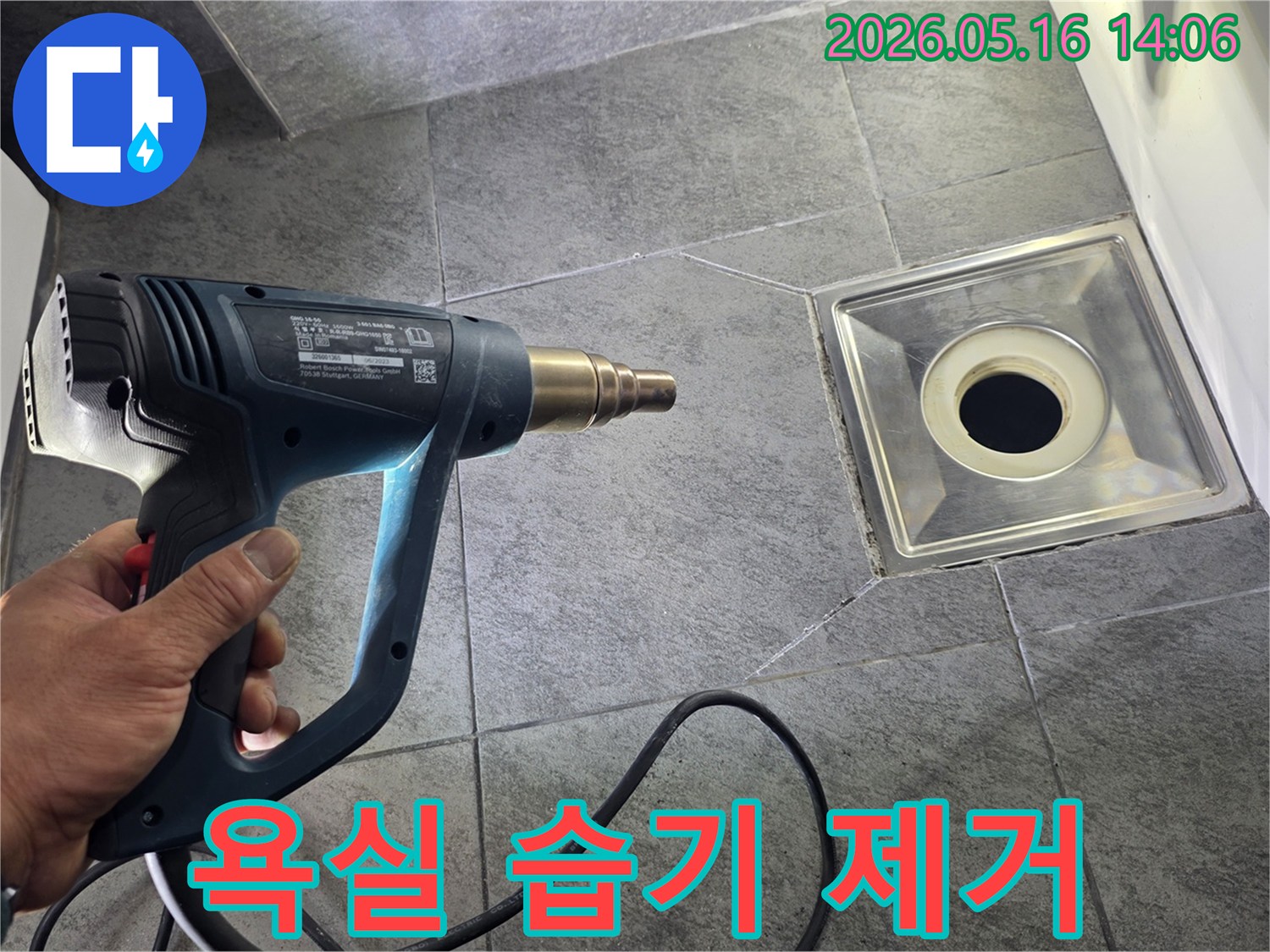누수 전문가가 욕실 바닥의 배수구 주변을 열풍기로 건조하여-습기를 제거하고 누수를 예방하는-모습입니다.