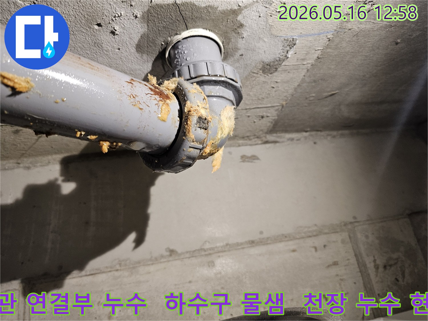 낡은 하수구 배관 연결부에서 물이 새고-노란 이물질이 흘러나오는 심각한 누수 현장입니다.