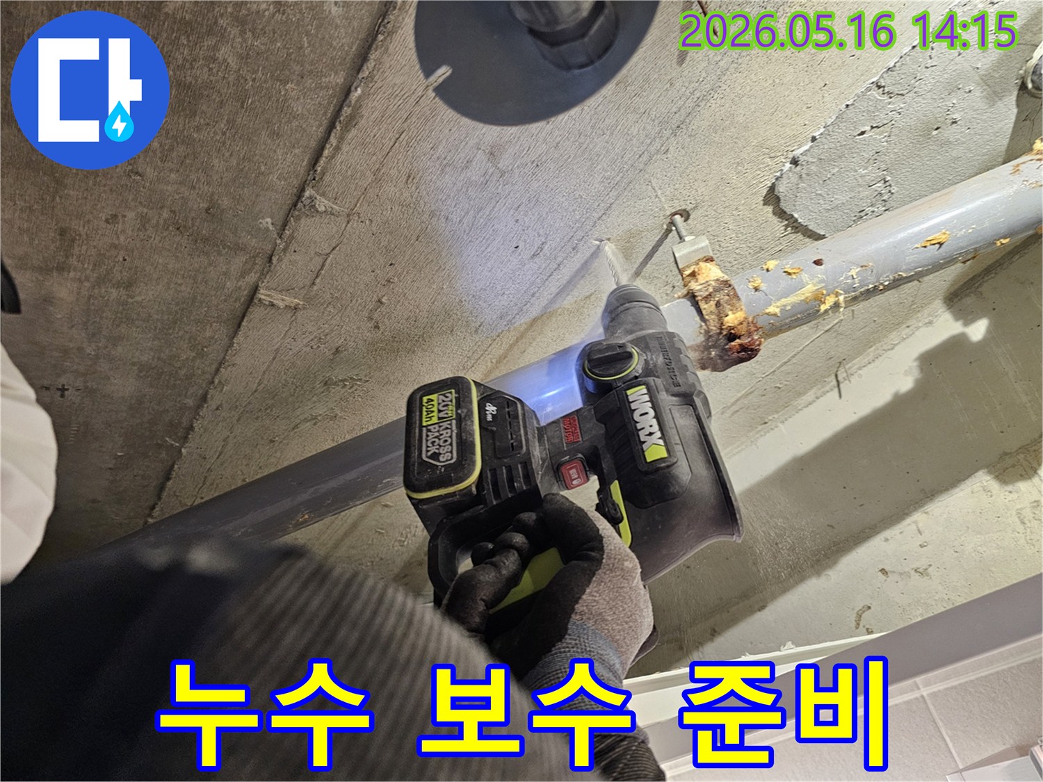 누수 전문가가 천장 배관의 누수 지점을 확인하고 보수를 준비하기 위해 드릴로 콘크리트를 타공하는 모습-정확한 보수를 위한 필수 단계입니다.
