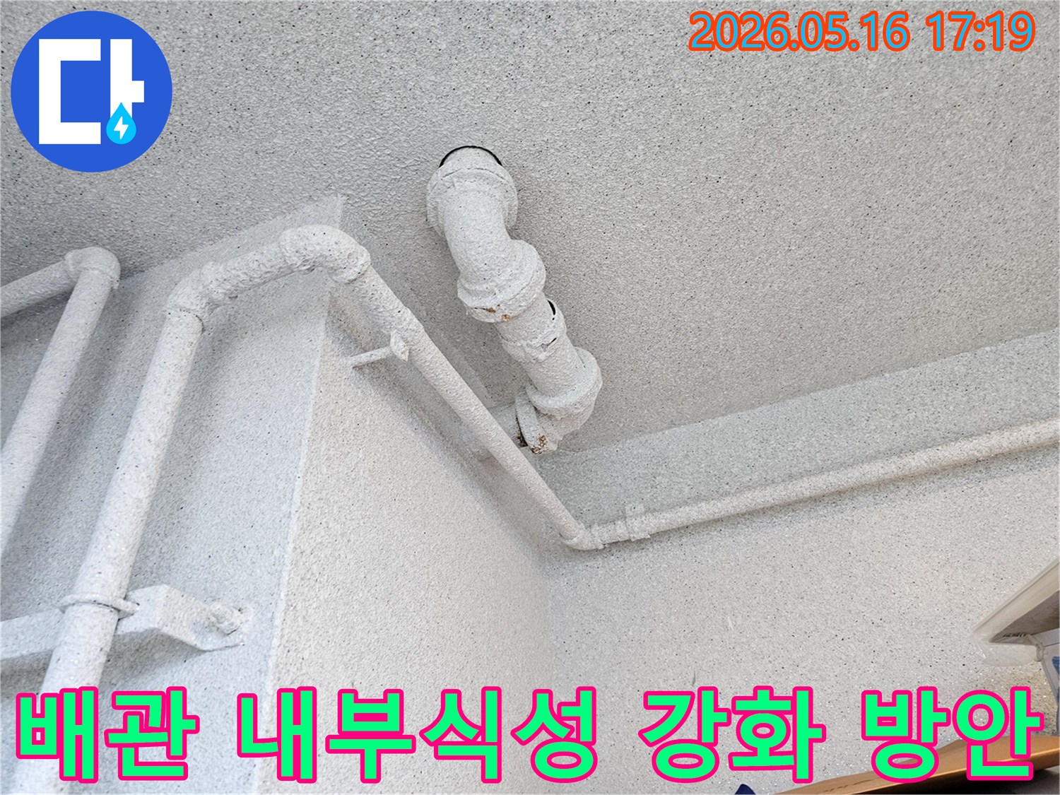 수원 장안구의 건물 천장에서-오래된 배관의 부식 상태를 확인하며-내부식성 강화 및 수명 연장 방안을-고객에게 설명하는-누수 전문가의 모습