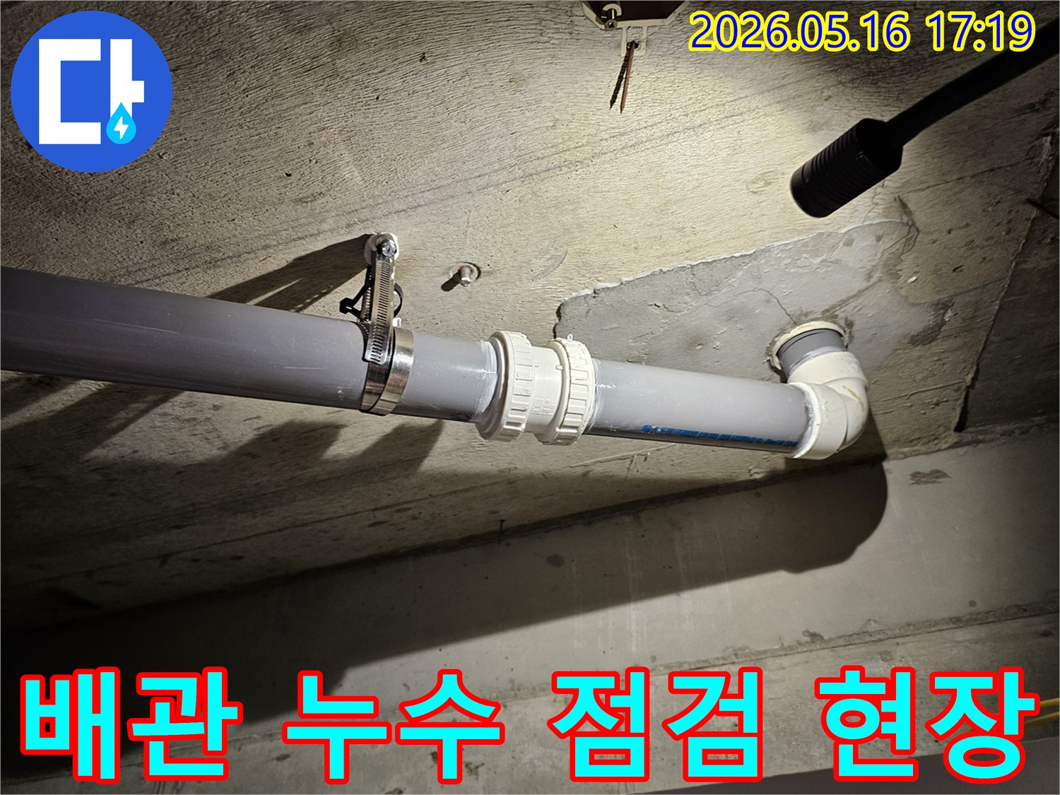 천장 배관의 연결 부위를-조명으로 비추며-꼼꼼하게 점검하는 현장 사진