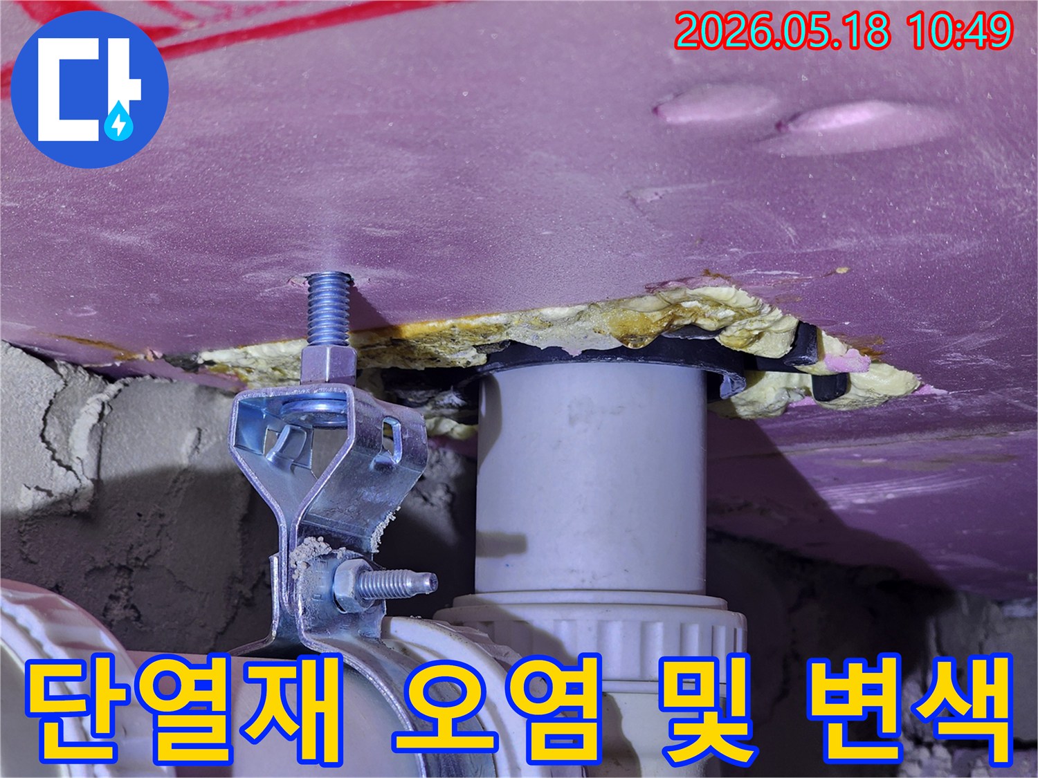 핑크색 단열재가 물에 젖어 누렇게 변색된 모습과-주변 배관의 상태를 보여주는-누수 현장 이미지입니다.