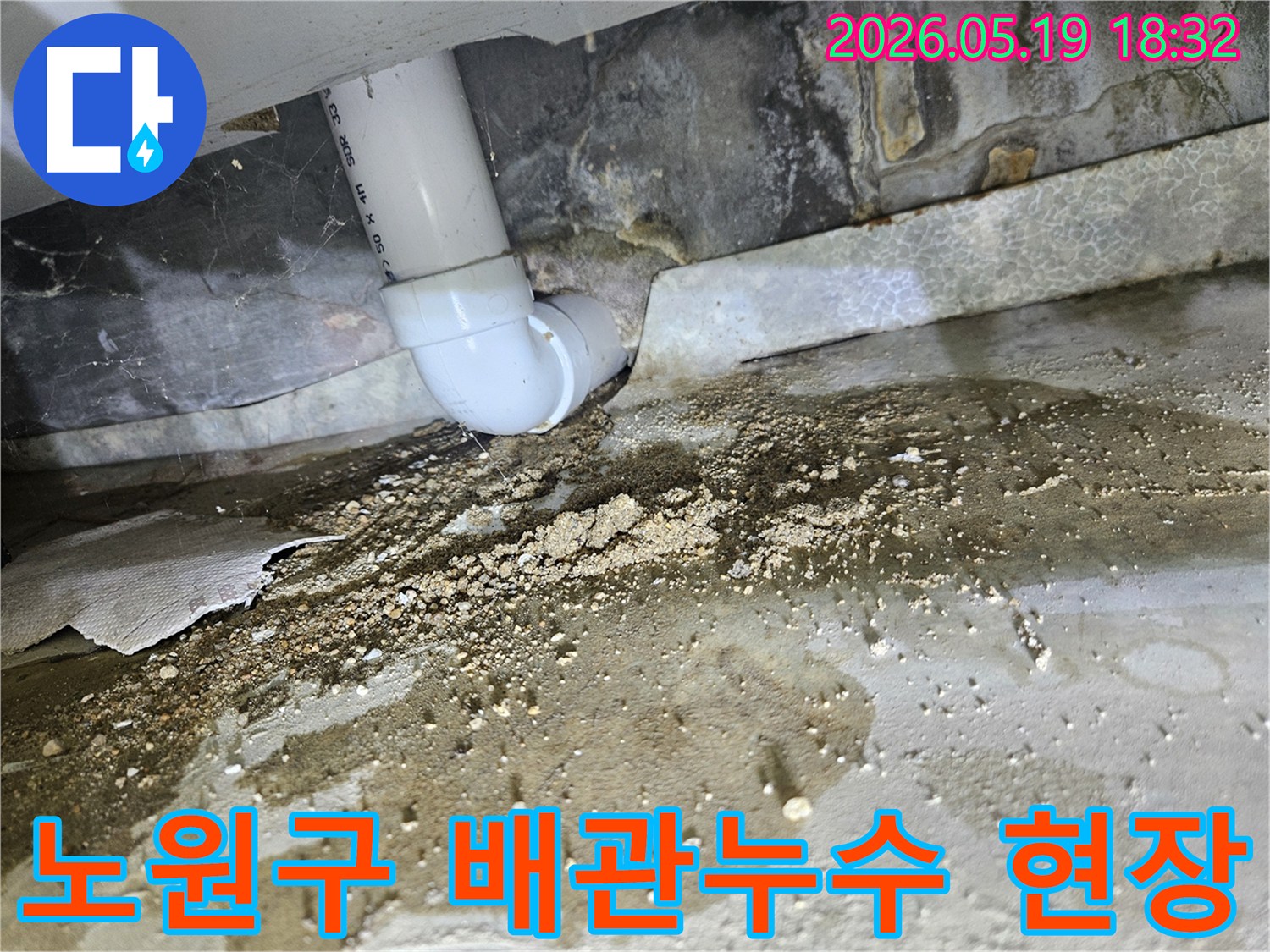 PVC 드레인 파이프의 연결 부위에서-물이 지속적으로 새어나와-주변 바닥과 벽면에 습기와-흙먼지가 쌓인-노원구 누수 현장의 모습입니다.