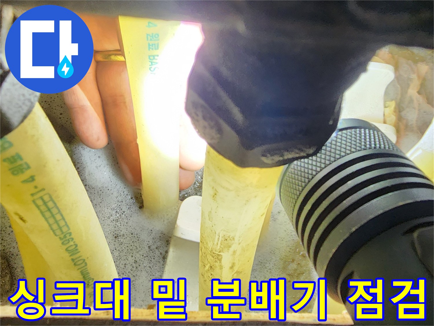밝은 손전등 빛으로-싱크대 하부의 배관과 분배기를 조사하는 과정