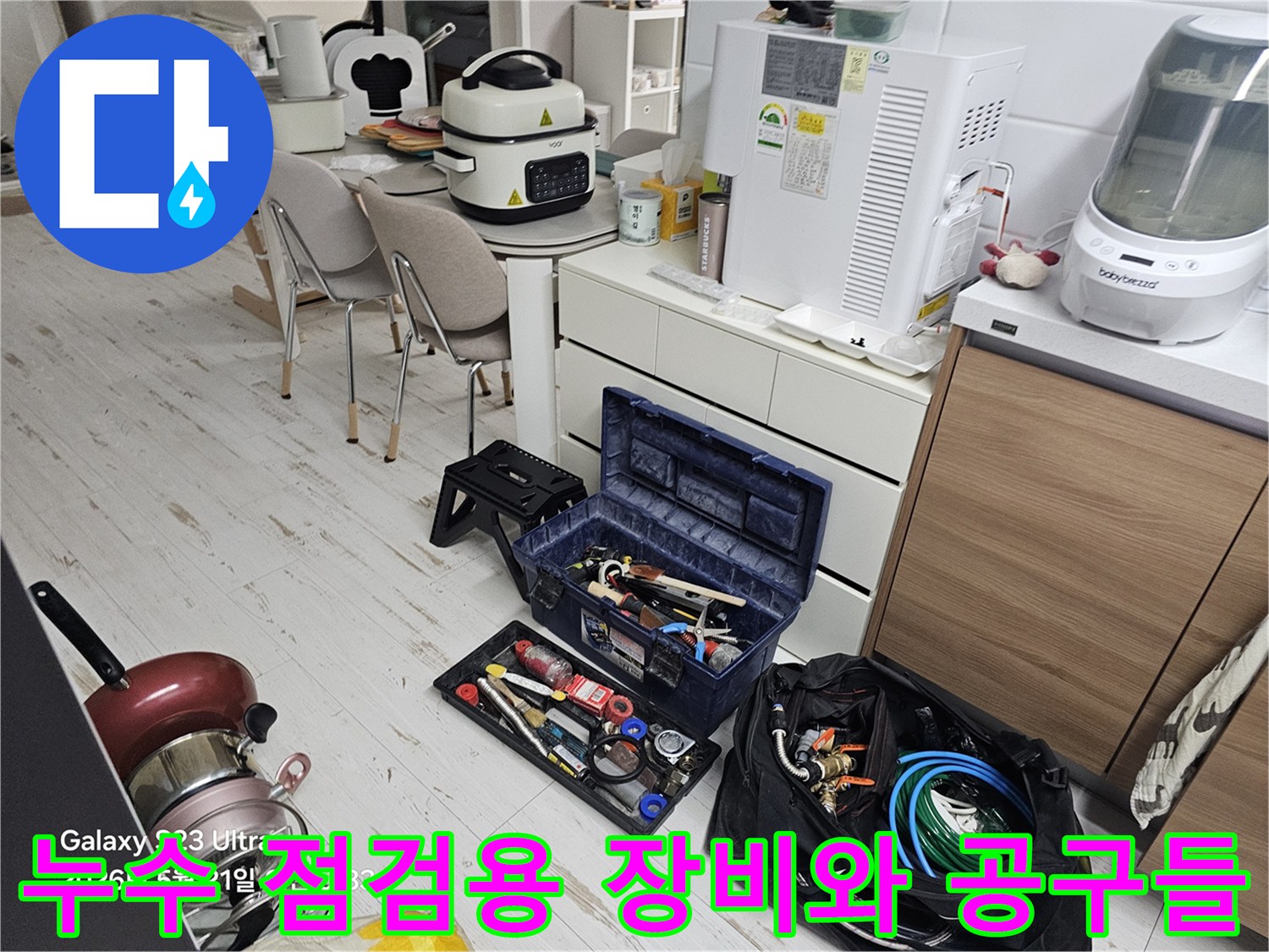 싱크대 하부장 점검을 위해 바닥에 준비된 수공구와 배관 관련 장비 세트