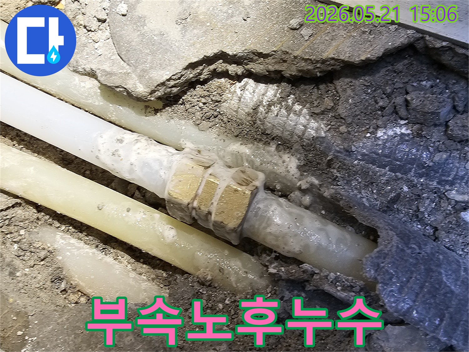 콘크리트 바닥 아래-오래된 수도 배관의-노후된 연결 부속에서-물이 새어 나와-주변을 적시고 있는-누수 현장의 모습입니다