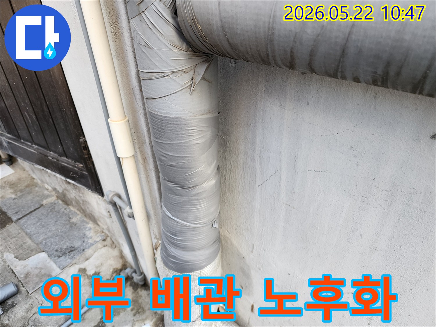 건물-외벽에-설치된-회색-배관의-보온재가-낡은-테이프로-감겨-있으며-전반적인-노후화가-진행된-모습입니다