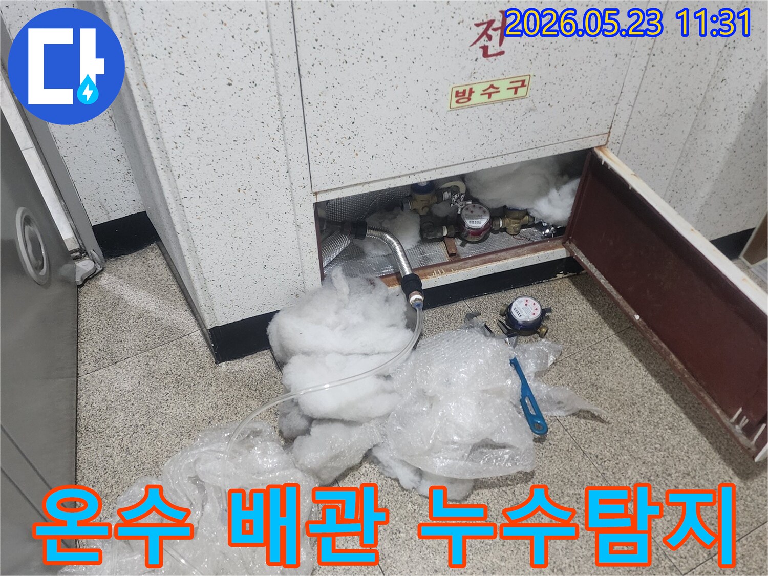 온수 배관의 누수 지점을 찾기 위해-압력 게이지와 탐지 장비를 설치하여-정밀하게 검사하는 모습입니다.