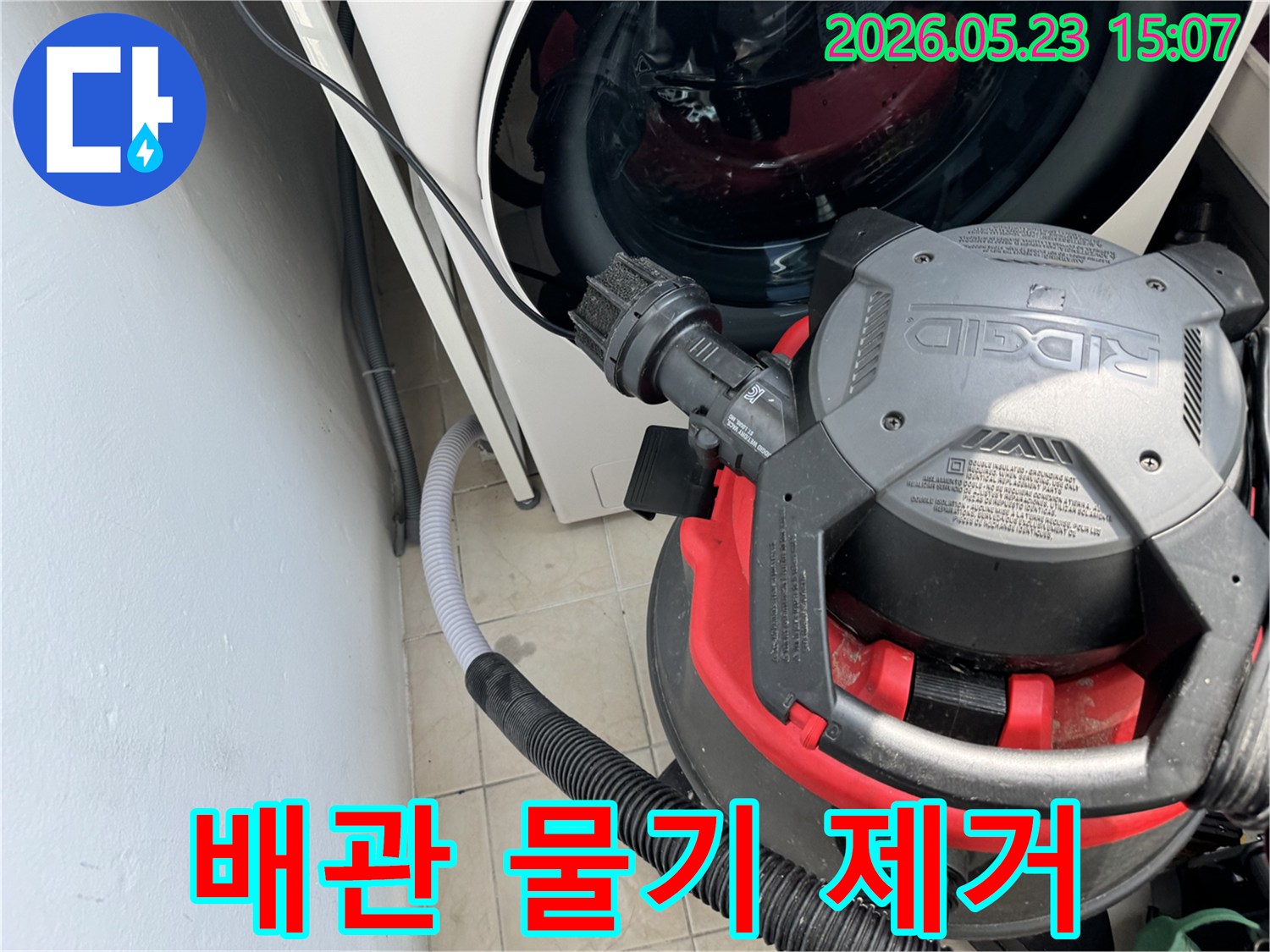 세탁기 옆-배수관 주변의 물기를-강력한 흡입기로 제거하는-누수 복구 현장 사진입니다
