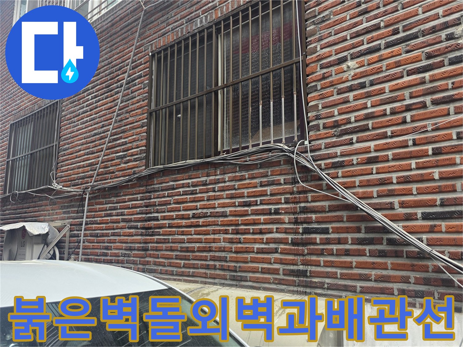 붉은색 벽돌로 마감된 건물 외벽과 창문 근처에 노출된 전선 및 배관 상태