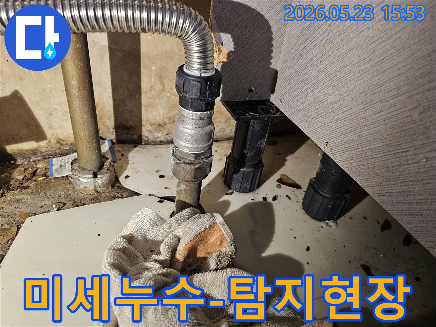 배관 연결 부위에서 물이 새어-바닥에 젖은 수건이 놓인-미세 누수 현장 사진