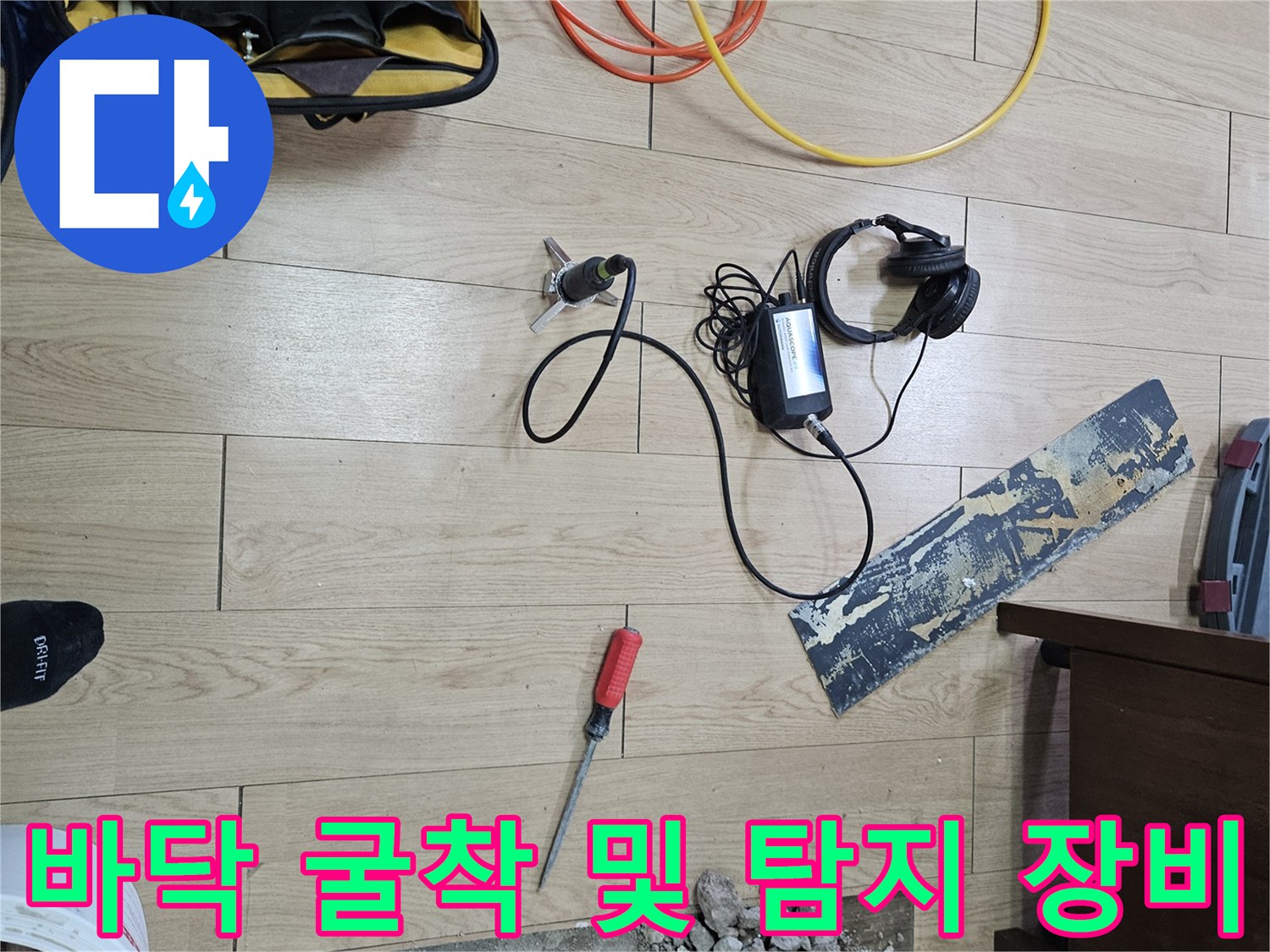 누수 지점 확인을 위해 마루를 들어내고 굴착한 현장-가스 탐지 장비와 공구가 놓여 있습니다.