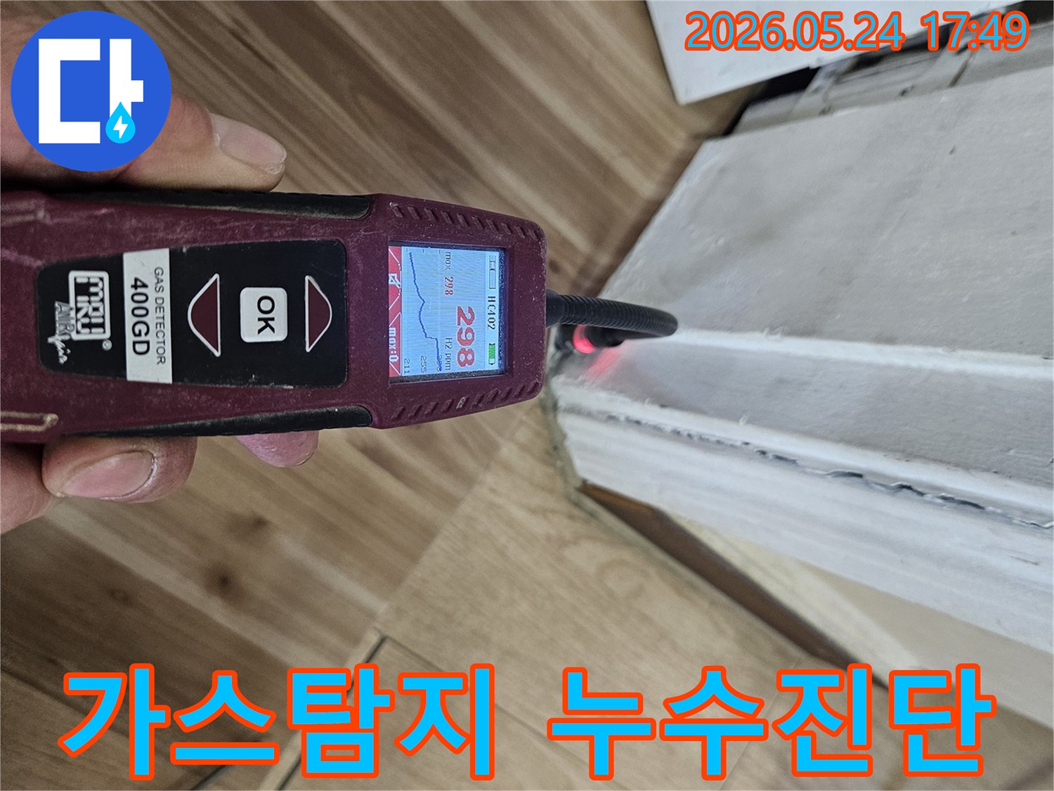 숙련된 누수 엔지니어가 가스 탐지기를 사용하여 벽면 하단에서 누수 반응을 면밀히 확인하고 있습니다.