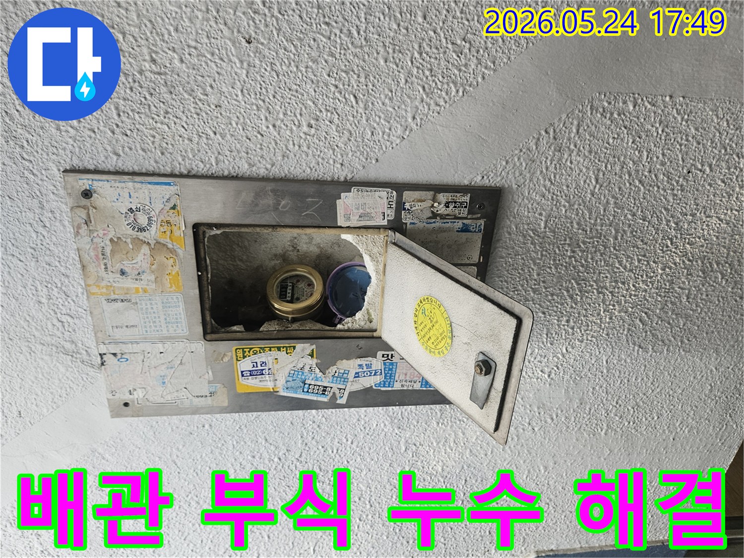 오래된 수도계량기함이 열려있고-내부 배관의 심각한 부식으로 인한-누수 현장을 보여주는 이미지입니다.
