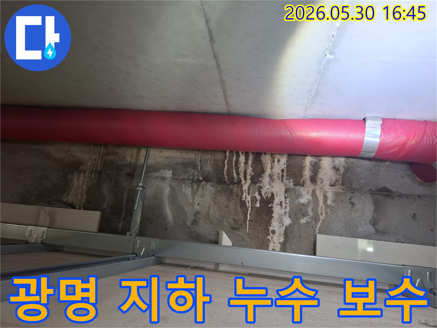 광명 아파트 지하 천장에서- 붉은 배관 아래로 보이는- 콘크리트 물자국을- 제거하고 보수하는 작업 현장
