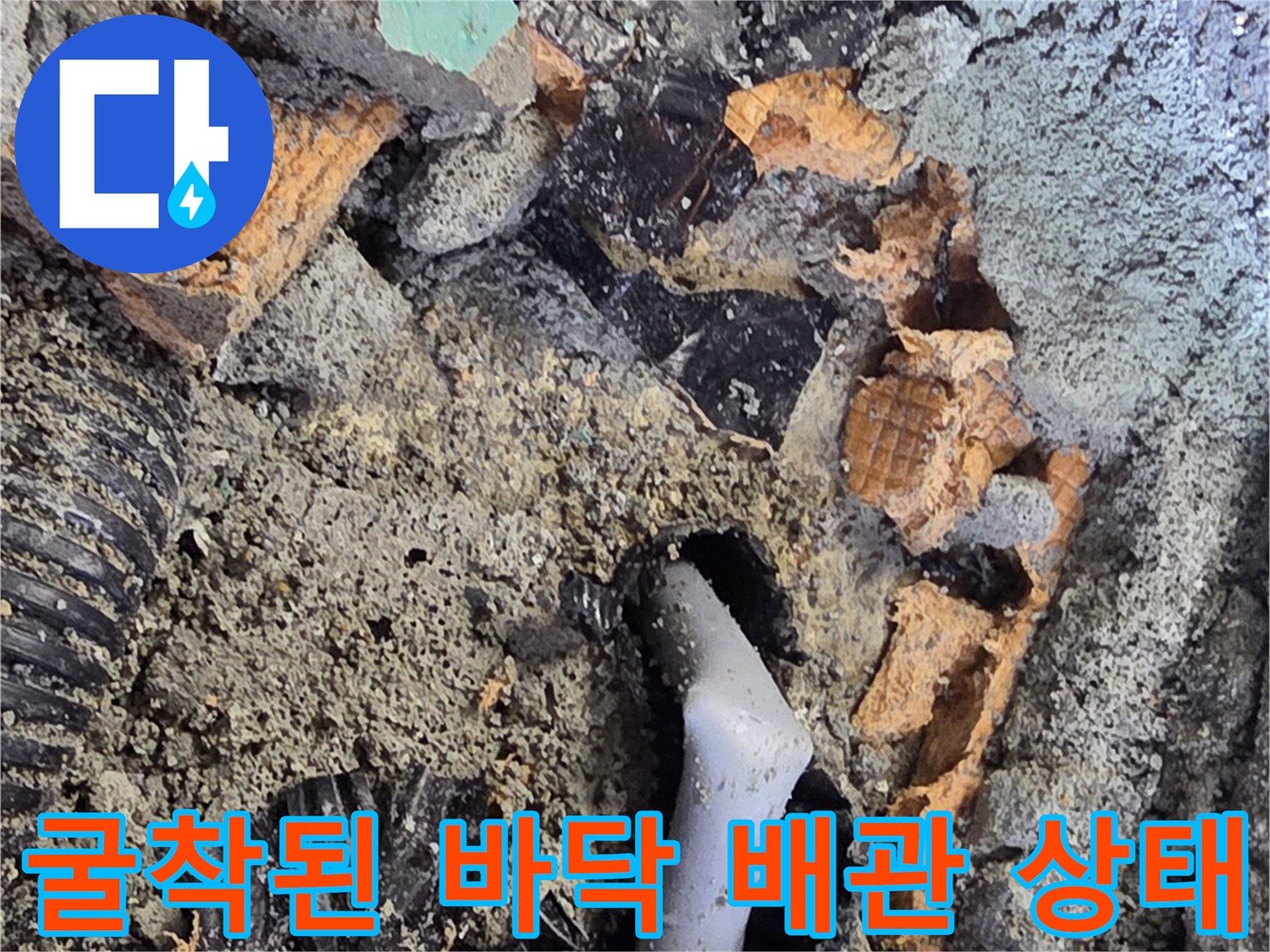 콘크리트 층 아래에 노출된 파손된 회색 배관 부속