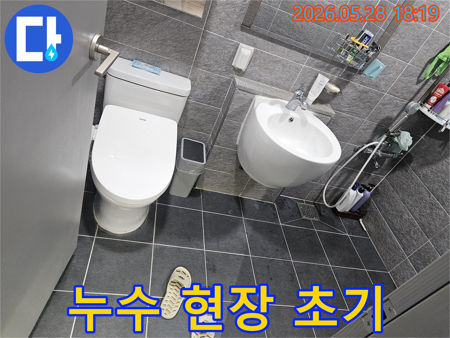 회색 타일로 이루어진 욕실 내부-변기와 세면대-그리고 샤워 공간이 보이는-누수 점검 전의 깨끗한 모습입니다.
