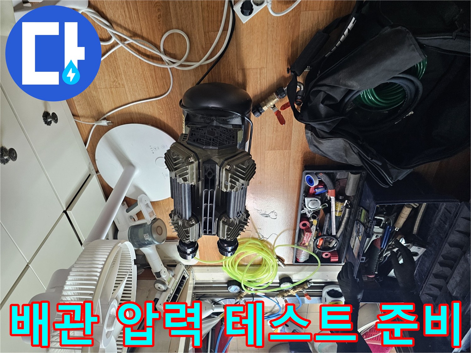 누수 지점을 찾기 위해 바닥에 배치된 컴프레셔와 각종 배관 공구 세트
