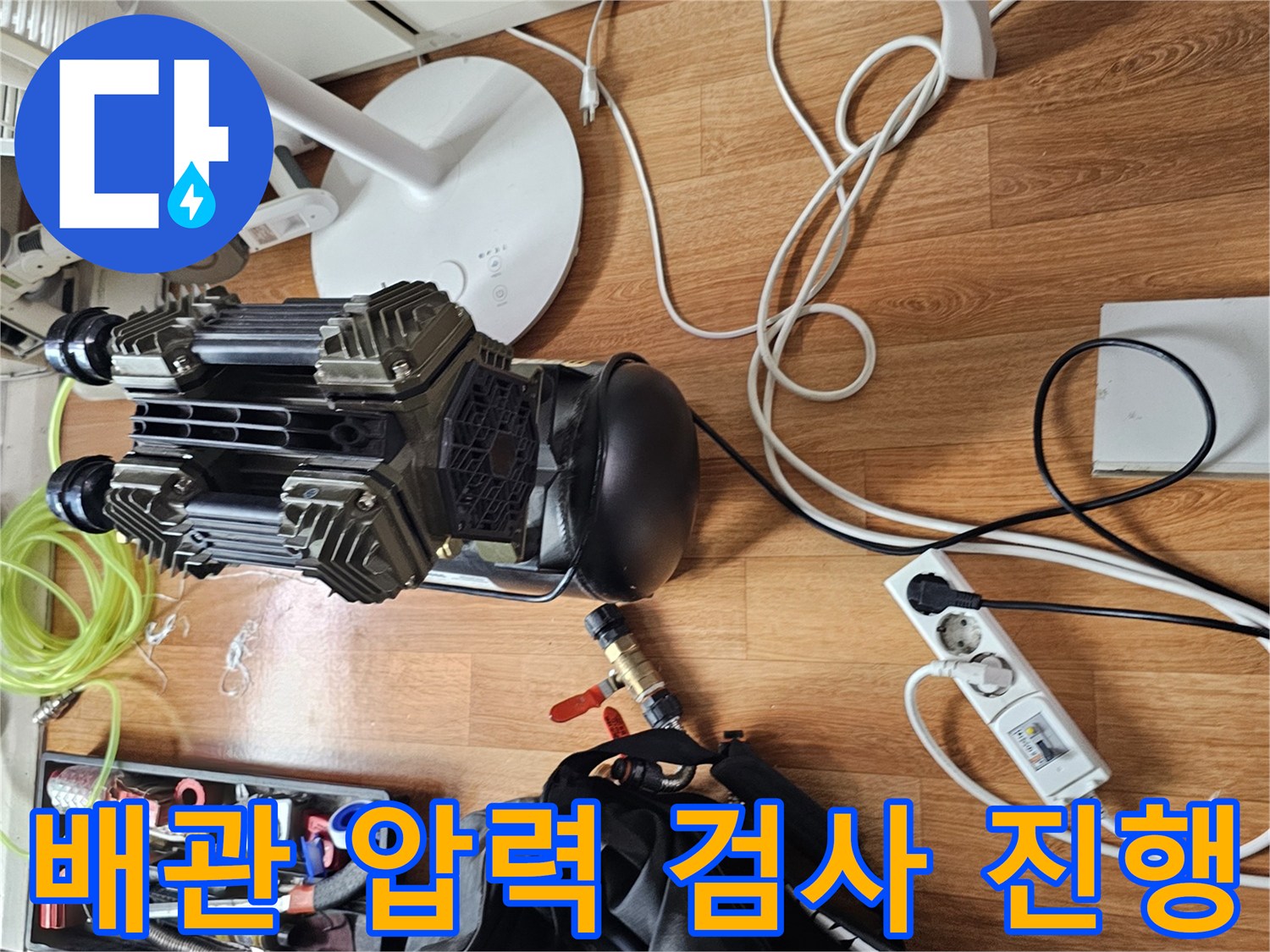 싱크대 주변 바닥에 놓인 배관 점검 게이지와 각종 수리 공구