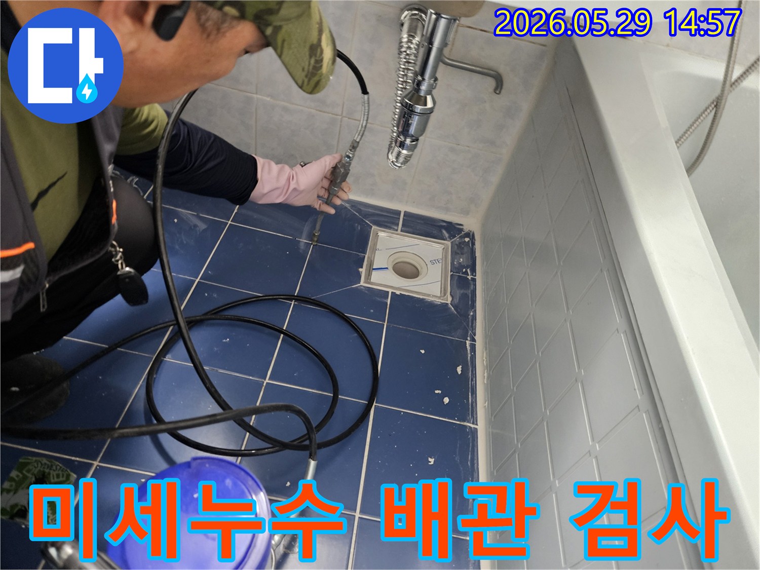 누수 전문 엔지니어가 욕실 바닥 배수구에 특수 장비를 삽입하여 미세한 누수 지점을 정밀하게 검사하는 모습입니다-정확한 진단을 위한 필수 과정입니다