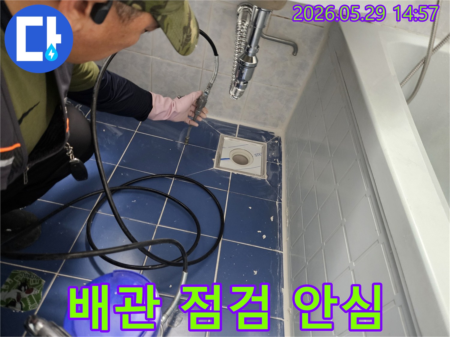 누수 전문 엔지니어가 욕실 바닥 배수구에 특수 장비를 삽입하여 배관 내부를 정밀하게 점검하며 고객에게 안심을 드리는 모습입니다-정확한 진단으로 걱정을 덜어드립니다